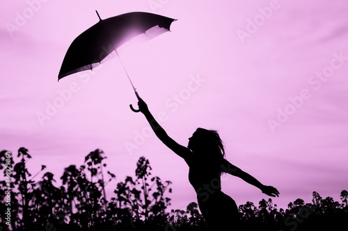 Unplugged free silhouette woman with umbrella up to pink sky. Nature girl at windy rainy day has adventure wanderlust. Wonderful scene of imagination power and departure to new horizons in youth