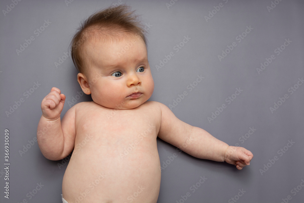 Newborn baby lying over gray background. Newborn baby skin care. Newborn baby lying over gray background. Newborn baby skin care.