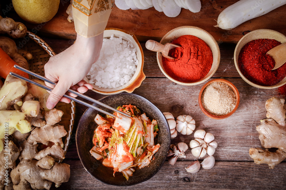 Girl wearing hanbok, holding chopsticks to taste kimchi In a tile bowl. Concept of Korean Fermented Cooking. Top view Girl wearing hanbok, holding chopsticks to taste kimchi In a tile bowl. Concept of Korean Fermented Cooking. Top view