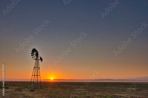 Sunrise silhouette of a windmill in a meadow