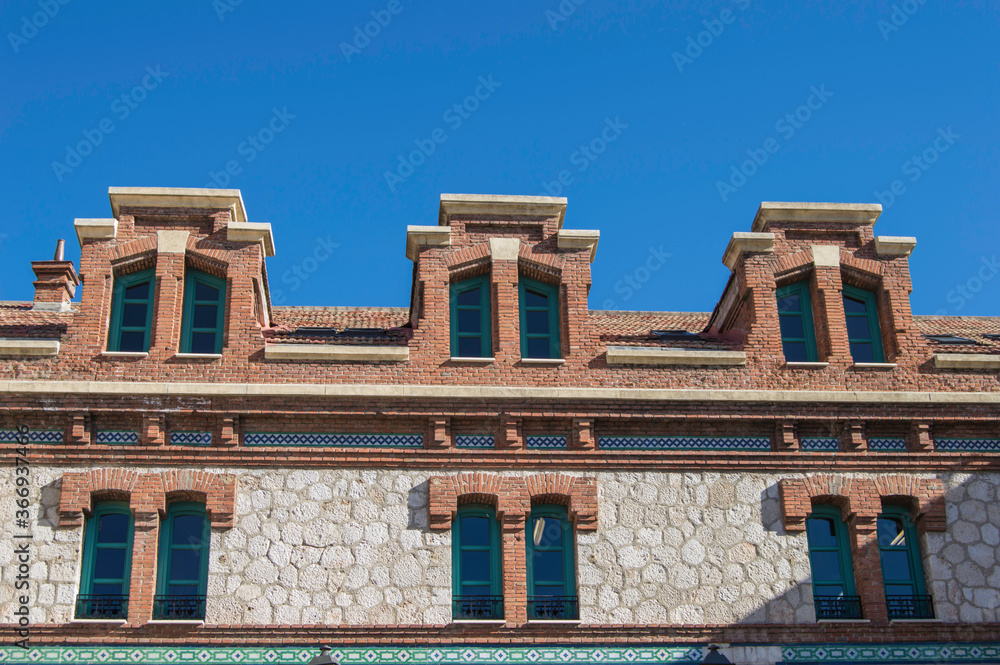 brick and stone facade with green frame paired windows in a 19th century building in Madrid. Spain