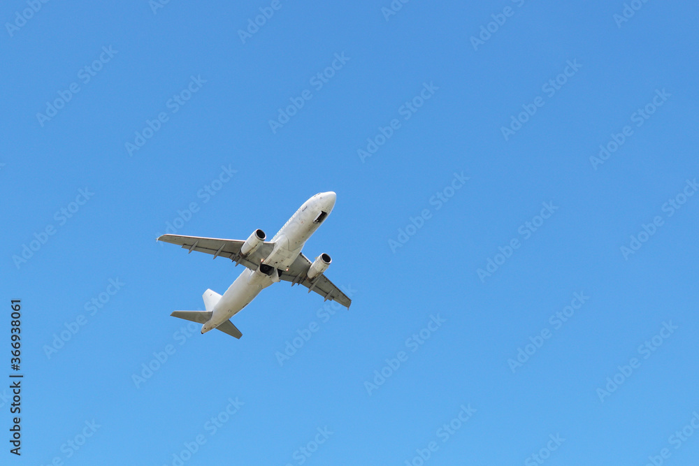 Airplane flying in the clear blue sky, bottom view. Commercial plane taking off Airplane flying in the clear blue sky, bottom view. Commercial plane taking off