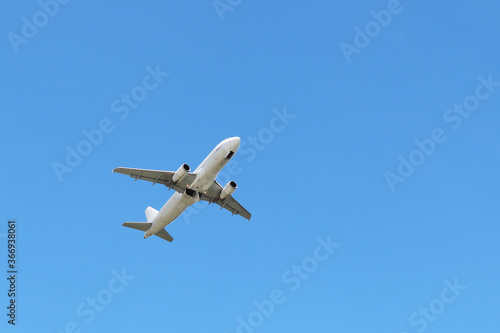 Airplane flying in the clear blue sky, bottom view. Commercial plane taking off