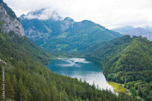 View to Leopoldsteinersee mountain lake with turquoise crystal clear water surrounded by forest in beautiful alpine landscape.