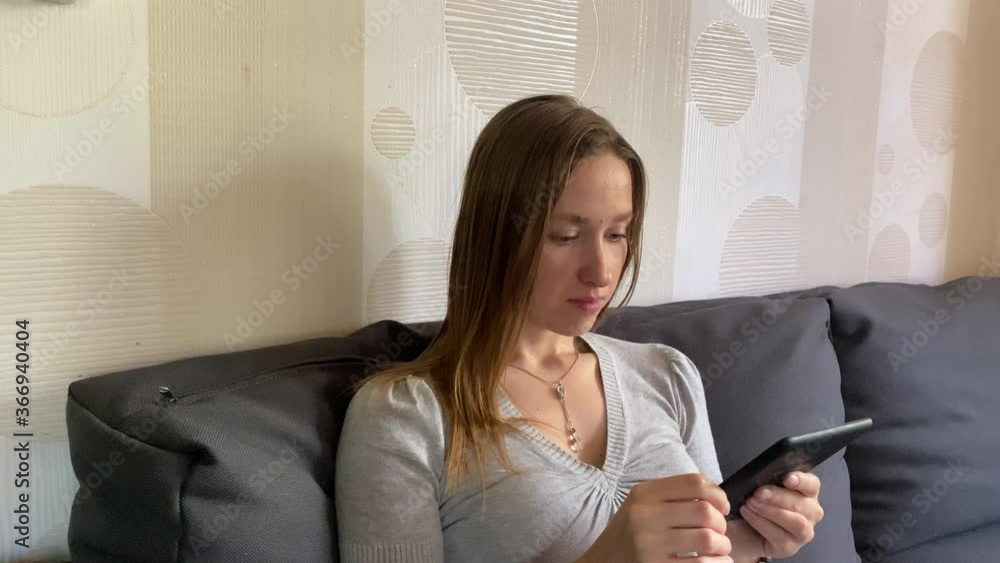 Girl reading electronic book at home on the sofa Girl reading electronic book at home on the sofa