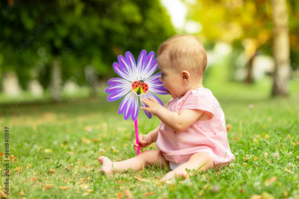 little baby girl 7 months old playing on a green lawn in a pink bodysuit, walking in the fresh air, early development of children up to a year little baby girl 7 months old playing on a green lawn in a pink bodysuit, walking in the fresh air, early development of children up to a year