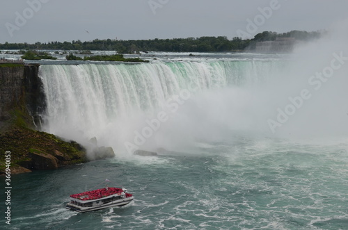 Niagra falls on a cloudy day, red passenger boat. 