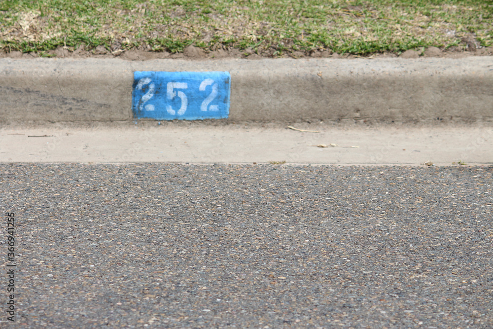 Foto de House number stencil painted onto the kerb of a bitumen road