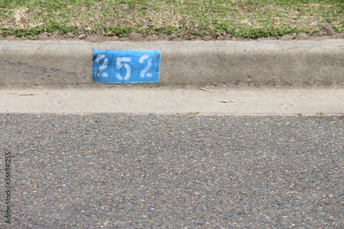 House number stencil painted onto the kerb of a bitumen road. Kurnell, Sydney