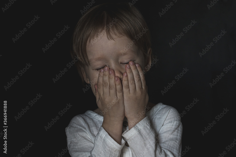Portrait of a scared little boy child. The kid covered his mouth with his hands, closed his eyes. The concept of stuttering, silence due to stress and shock. banner, copy space. Portrait of a scared little boy child. The kid covered his mouth with his hands, closed his eyes. The concept of stuttering, silence due to stress and shock. banner, copy space.