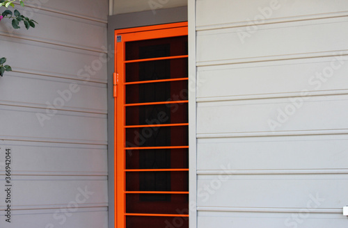 Canvas Print Bright orange screen security door on a weather board house