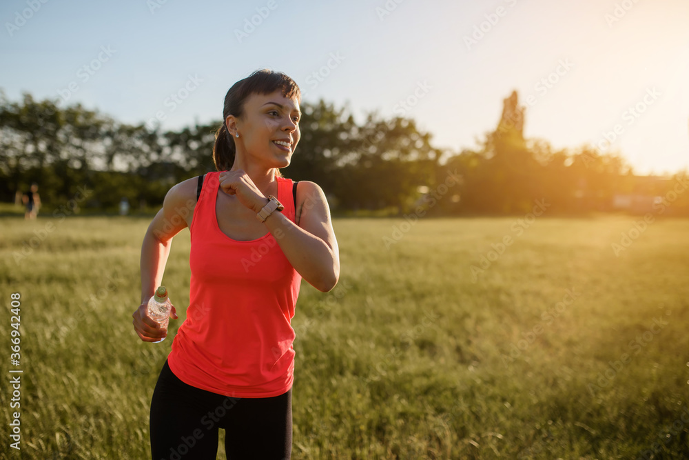 Young beautiful woman is making sport, she is running on a grass in the midst of nature on sunset. Young beautiful woman is making sport, she is running on a grass in the midst of nature on sunset.