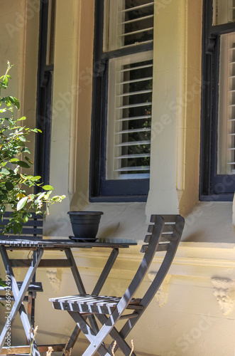 Canvas Print Front veranda of a beige victorian house with grey patio seating