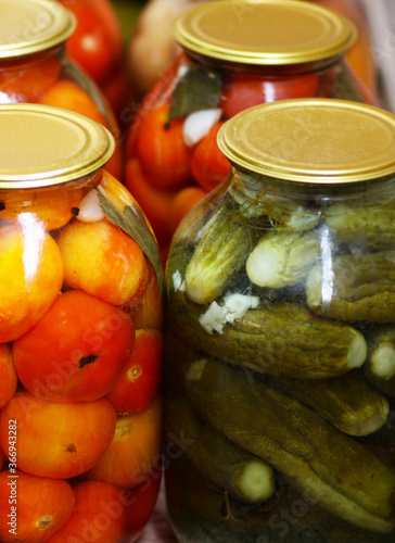 Glass containers with tomatoes and green cucumbers.