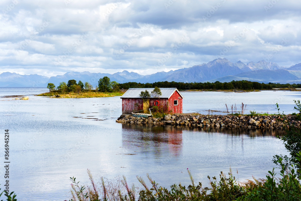Norwegian coast landscape with a typical red house. Wooden red houses are called rorbu or rorbuer and are used for fishermen or tourists. Lofoten, Norway