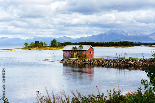 Norwegian coast landscape with a typical red house. Wooden red houses are called rorbu or rorbuer and are used for fishermen or tourists. Lofoten, Norway