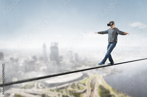 Man wearing virtual reality goggles and balancing on rope