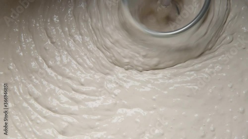 Slow motion pan shot of mixing concrete plaster with electric mixer. spatula and bucket with mortar on the construction site.
