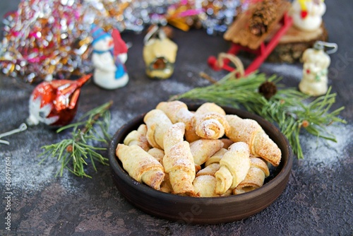 Cottage cheese biscuits in the shape of bagels in a brown ceramic bowl on a dark concrete background in the New Year and Christmas style.
