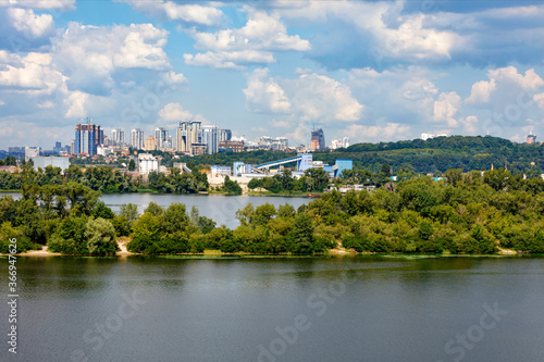 The beautiful cityscape of Kyiv with the Dnipro River and islands in the foreground and new high-rise buildings on the horizon.