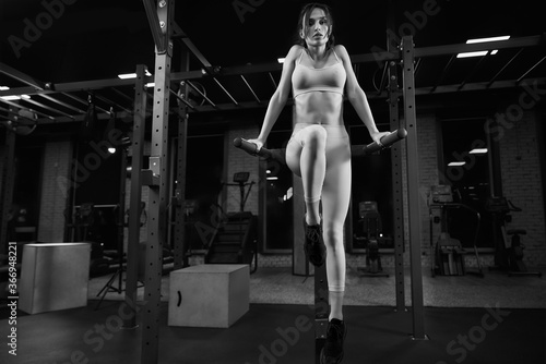 Woman posing on parallel bars in gym.