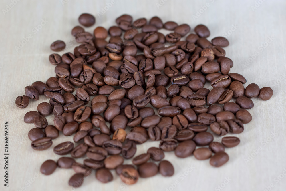 Naklejka premium Roasted coffee beans on a wooden background. Coffee and light wood background. Seeds.