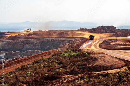 Open pit mine in Africa, with huge crane and trucks to bring ore to a processing plant 