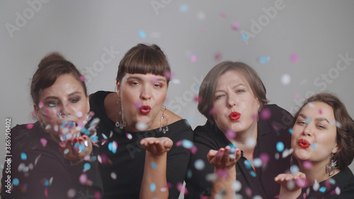 Tableau sur toile Beautiful overweight women blowing colorful confetti at camera isolated