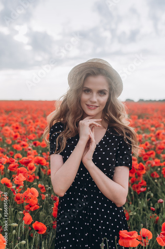 Beautiful woman natural face blondie hair casual female portrait in red poppy field in hat