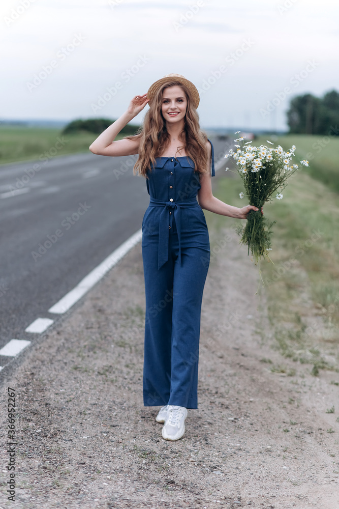 Beautiful blondie woman natural face in hat on the road with flowers Beautiful blondie woman natural face in hat on the road with flowers