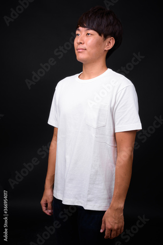 Young handsome Asian man against black background © Ranta Images