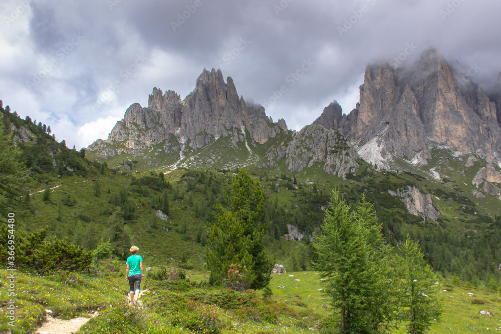 Incredible nature landscape in Dolomites Alps. Spring green blooming meadow. Panorama of Dolomites,Italy. Woman hiking in mountains.Active lifestyle.Girl backpacker,adventure vacations.Summer holiday