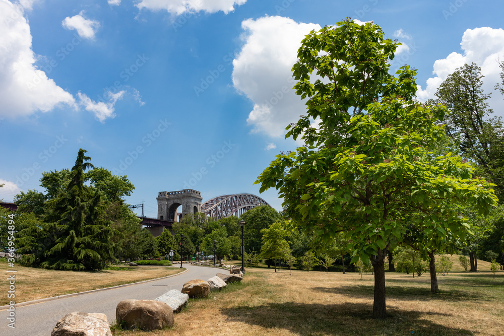 Empty Street on Randalls and Wards Islands with Green Plants and Trees during Summer with a view of the Hell Gate Bridge in New York City Empty Street on Randalls and Wards Islands with Green Plants and Trees during Summer with a view of the Hell Gate Bridge in New York City