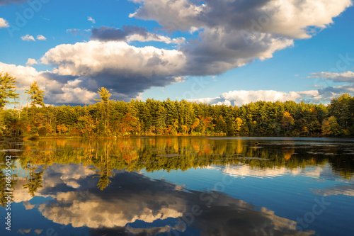 Colorful fall foliage with dramatic clouds and reflection in lake.