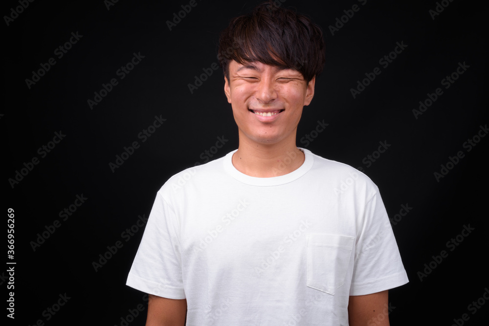 Young handsome Asian man against black background Young handsome Asian man against black background