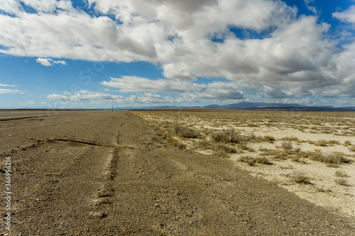 road leading in to distance with dramatic clouds overhead in desert