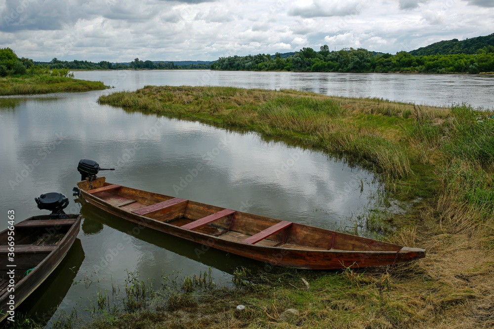 Obraz premium old fishing boats in the calm waters of the Vistula river at cloudy day