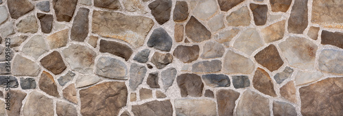 Wand aus braunen und grauen Natursteinen in verschiedenen Farbtönen und Formen