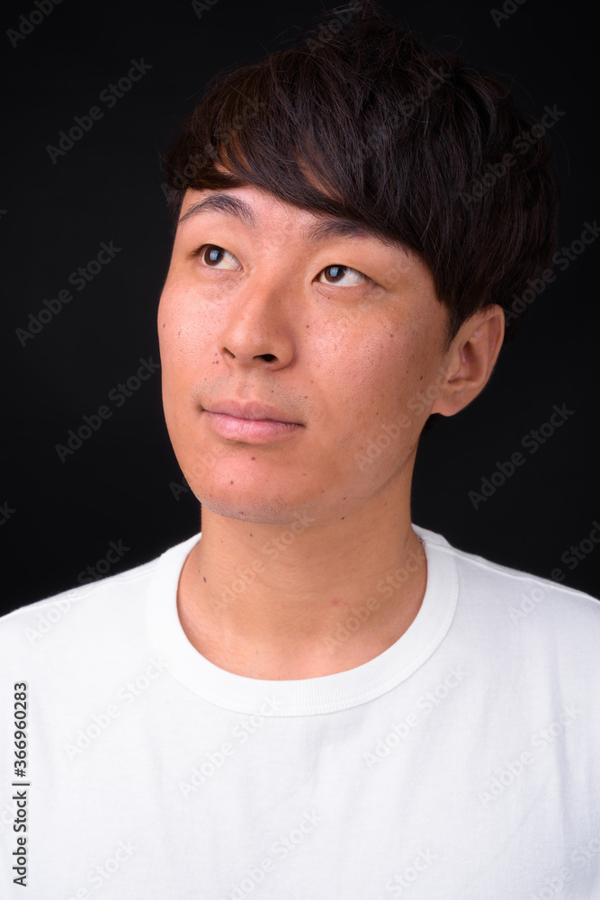 Fototapeta premium Young handsome Asian man against black background