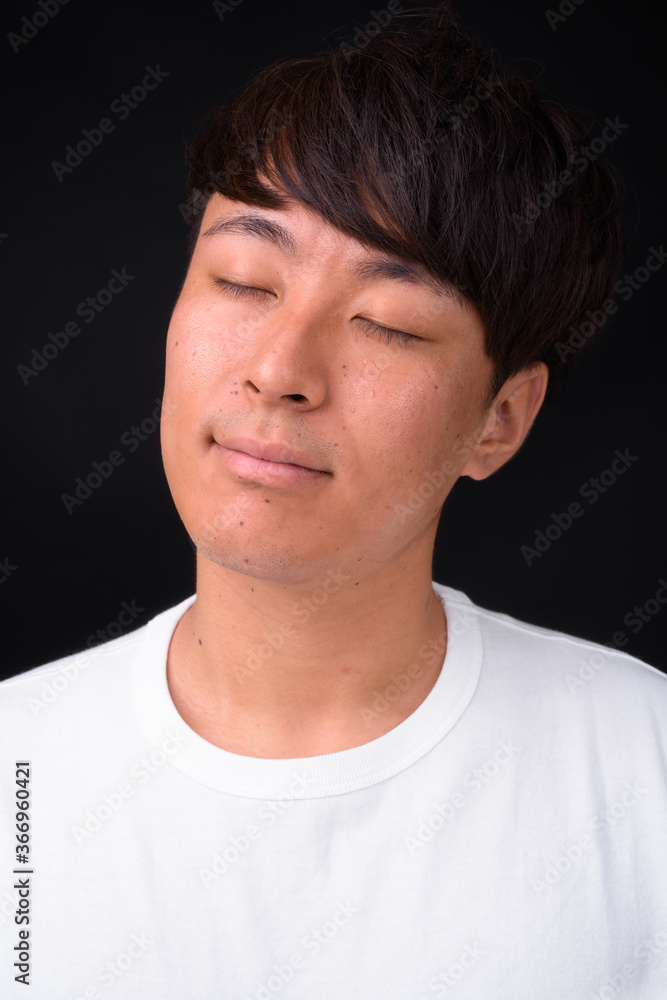 Fototapeta premium Young handsome Asian man against black background
