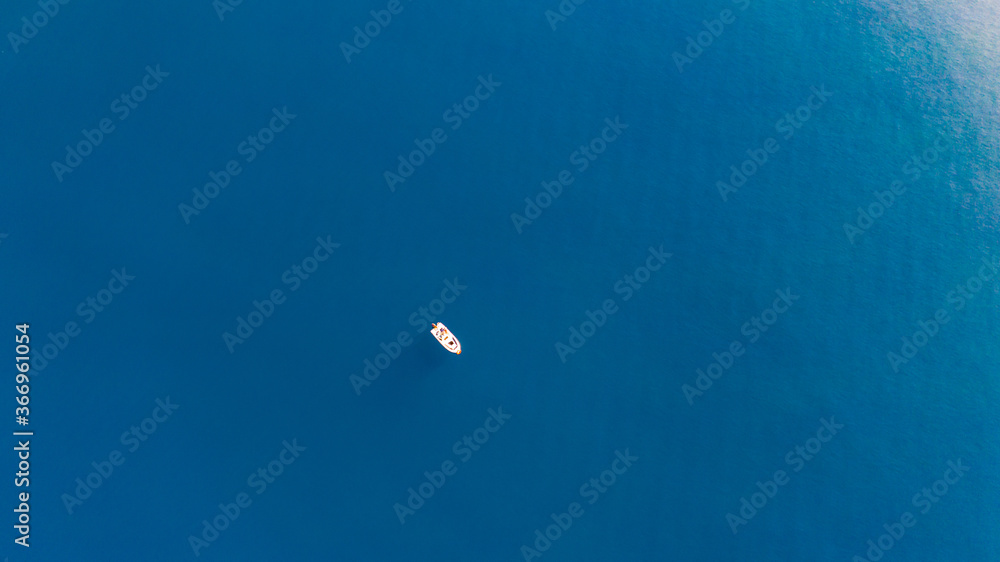 Aerial view of a small boat standing still in the middle of the blue waters of Aegean sea.