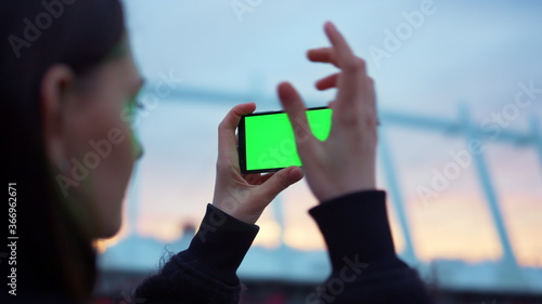 Woman taking selfie photo on smartphone with green screen. Mobile phone