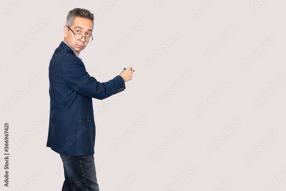 Businessman in glasses and a business suit is pointing marker to the side. Isolated gray background. Copy space Businessman in glasses and a business suit is pointing marker to the side. Isolated gray background. Copy space