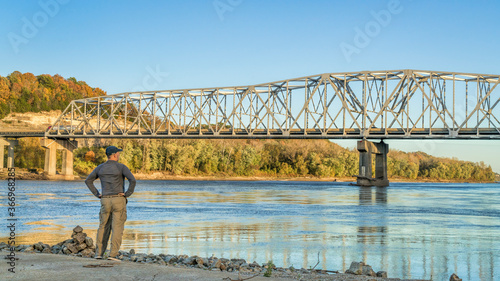 Lonely male figure at the old boat ramp on Missouri River at Taylor's Landing near Rocheport, MO, fall colors scenery with the bridge view photo