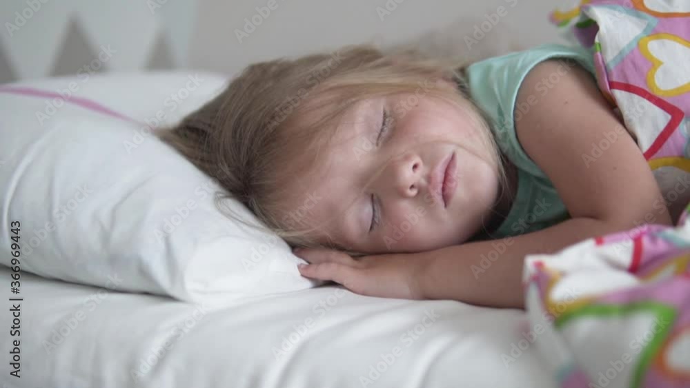 The little girl sleeps sweetly in her bed at home. Close-up of a sleeping child The little girl sleeps sweetly in her bed at home. Close-up of a sleeping child