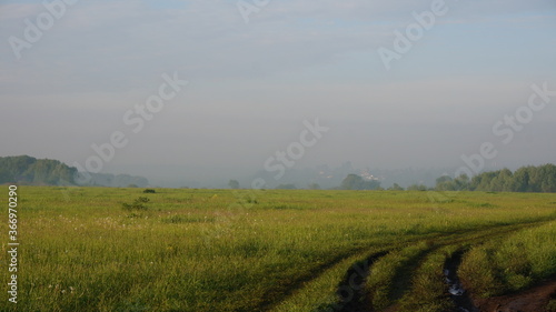 road in the field after the rain on the background of fog