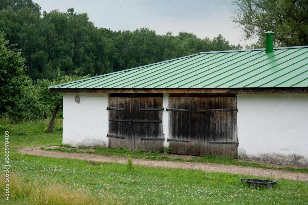 stone white old animal shed with metal green roof on forest background stone white old animal shed with metal green roof on forest background