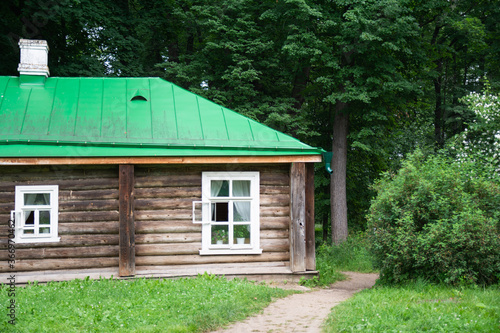 old wooden house with green metal roof on forest background