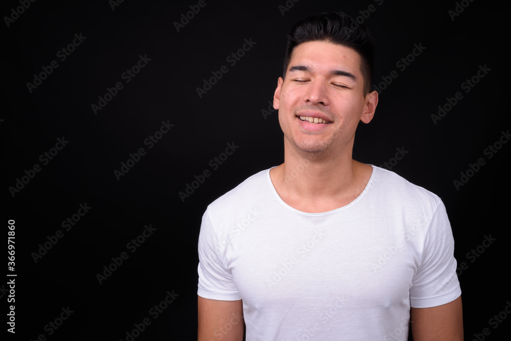 Young handsome multi ethnic man against black background Young handsome multi ethnic man against black background
