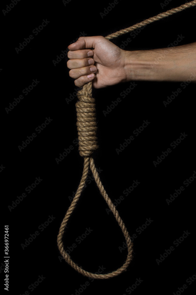 Hand holds a noose on a black background. Social problem. The end of the path Hand holds a noose on a black background. Social problem. The end of the path